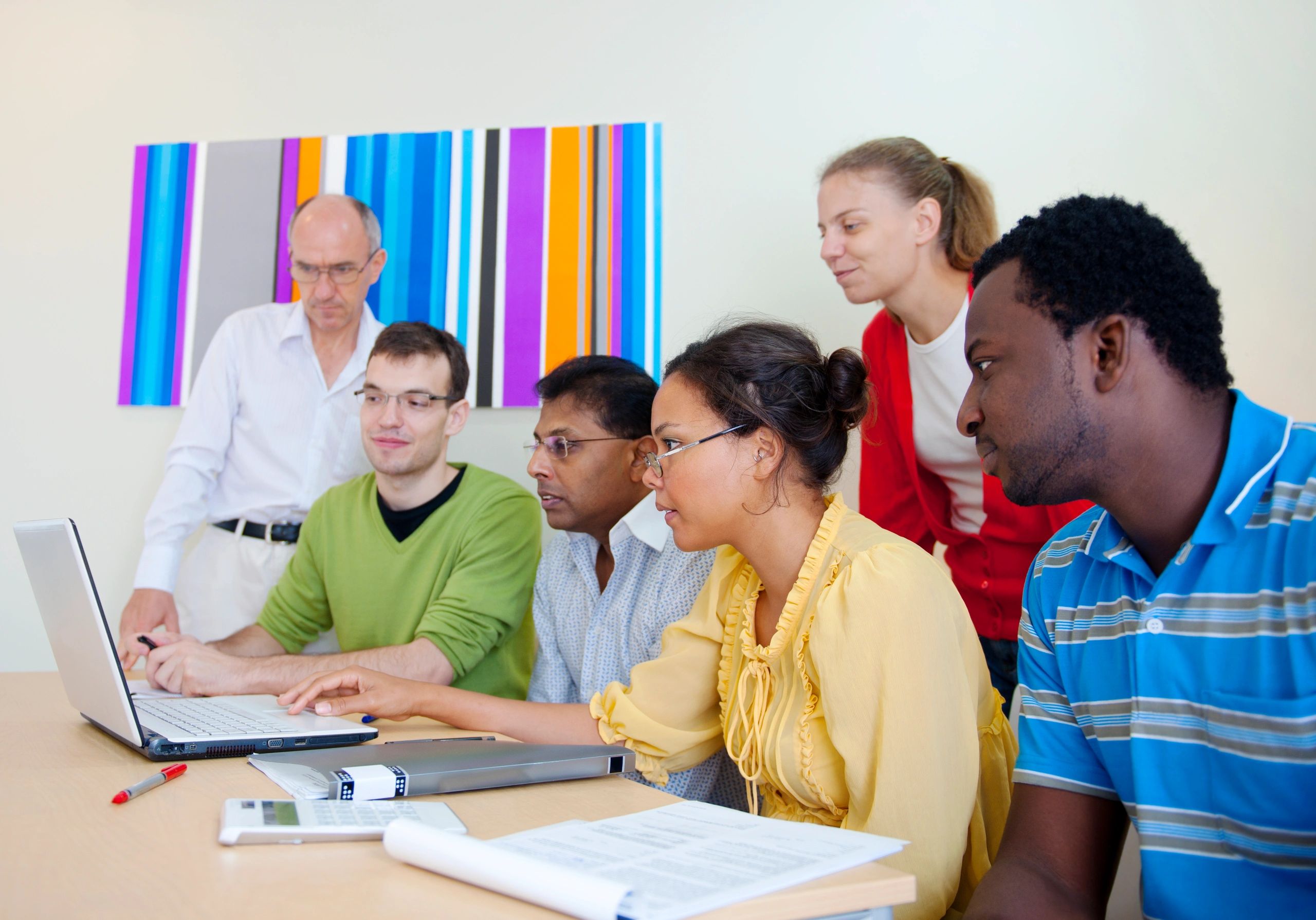 Adults collaborating around a laptop in a workshop