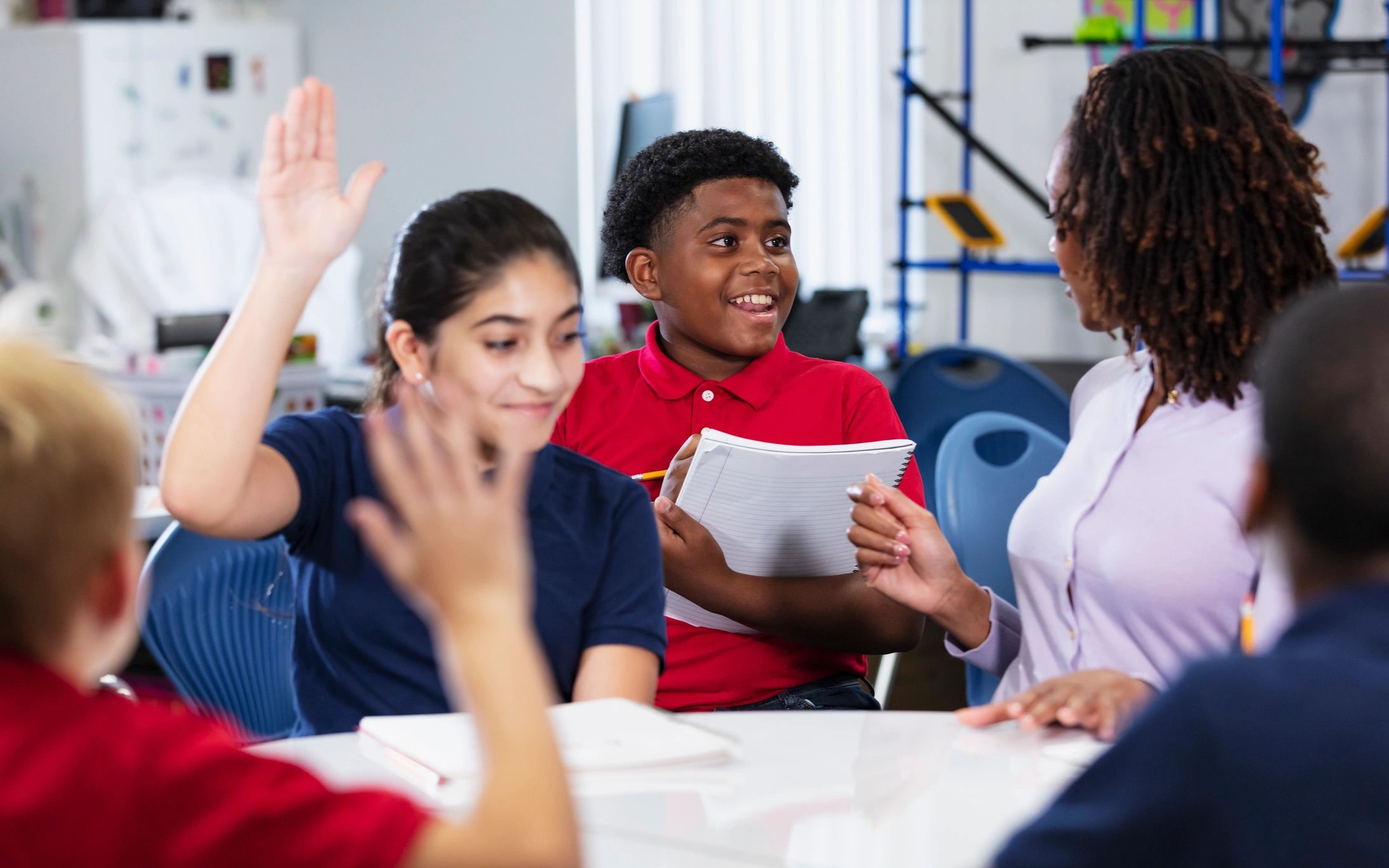 Middle school student talking with teacher during class discussion