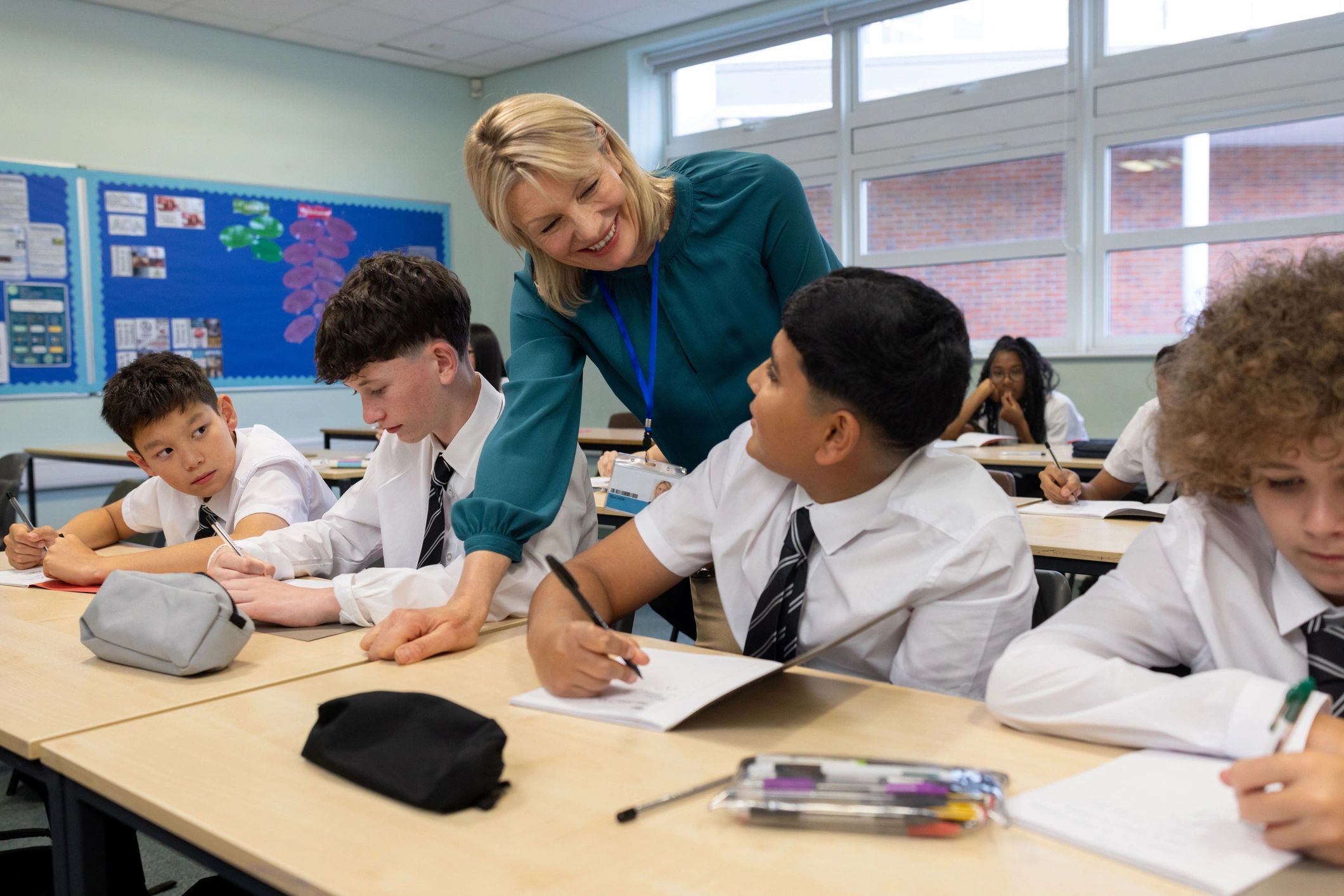 Teacher helping students in a bright classroom