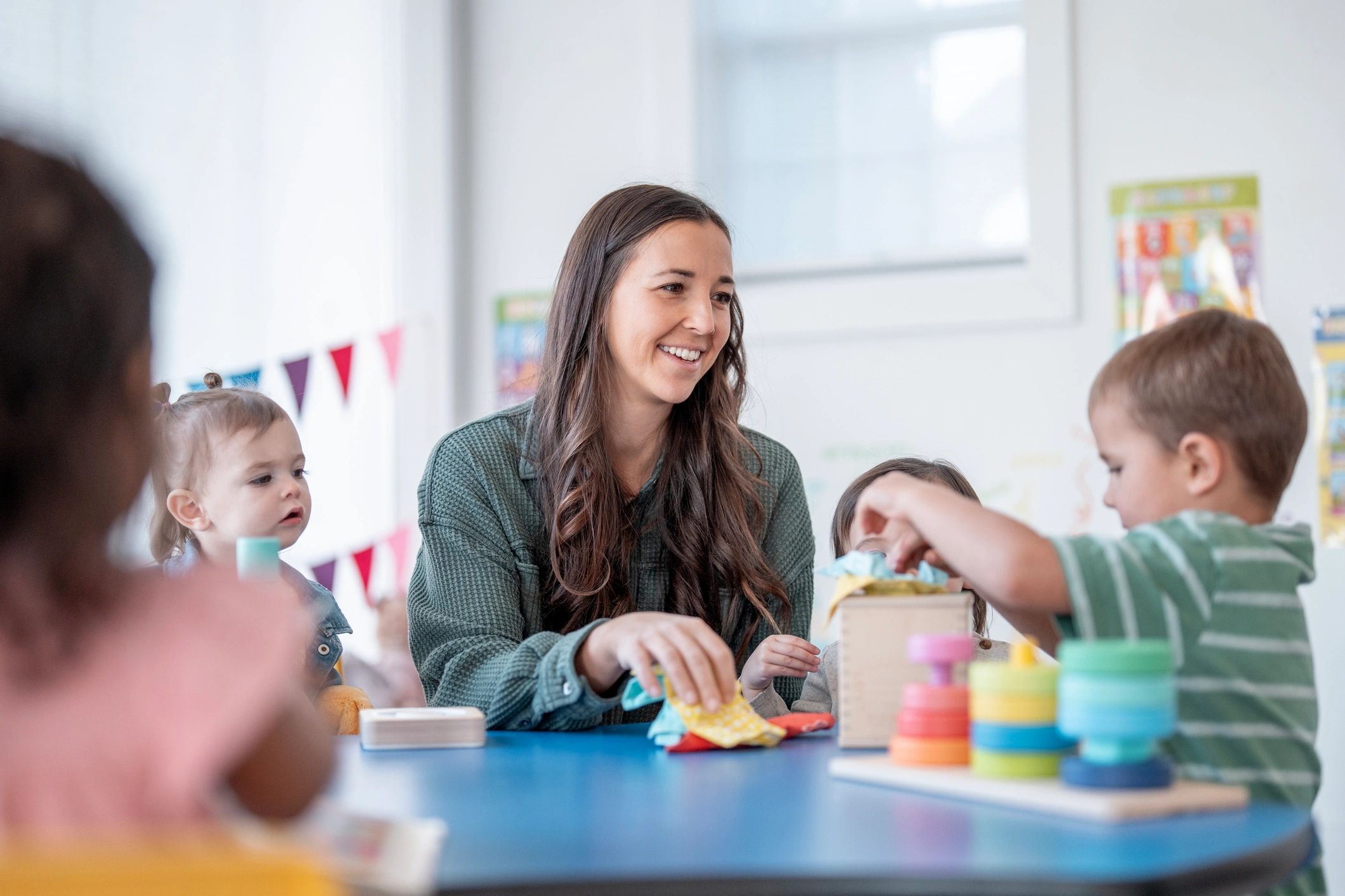 Teacher leading a small group of children in a colorful classroom