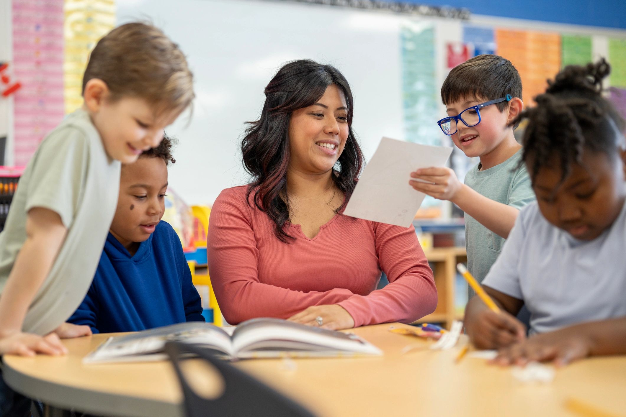 Teacher and students collaborating on math work at a table